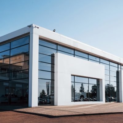 Modern car building. Many vehicles inside. Sunny day with clear sky.